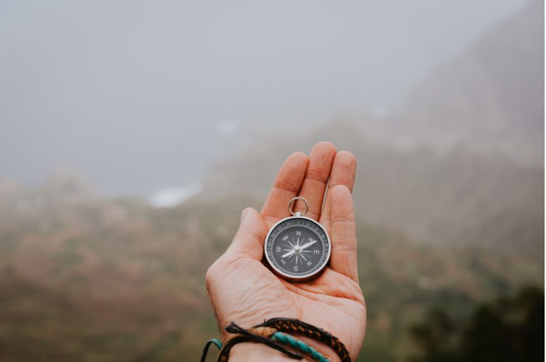 Looking at the compass to figure out right direction. Foggy valley and mountains in background. Santo Antao. Cape Cabo Verde