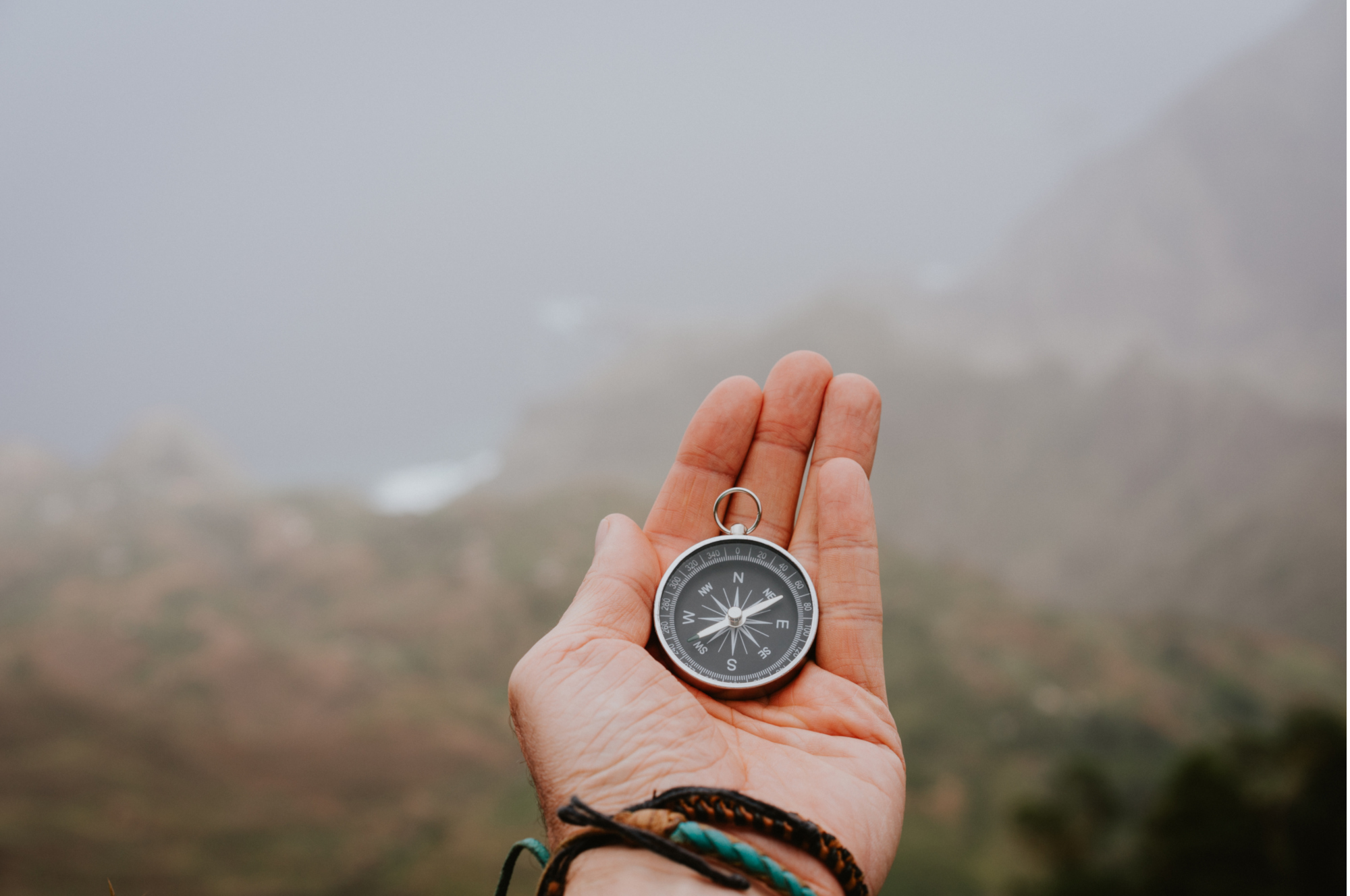 Looking at the compass to figure out right direction. Foggy valley and mountains in background. Santo Antao. Cape Cabo Verde